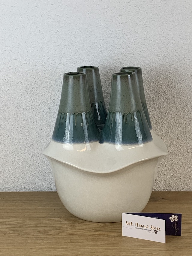Een unieke keramische Nils vaas met vier openingen in een aqua-groene en crème-witte kleur.