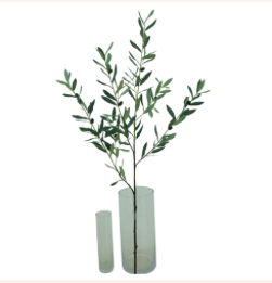 Een kunstmatige olijftak van 70 cm met smalle groene bladeren en kleine olijven, geplaatst in een glazen vaas.