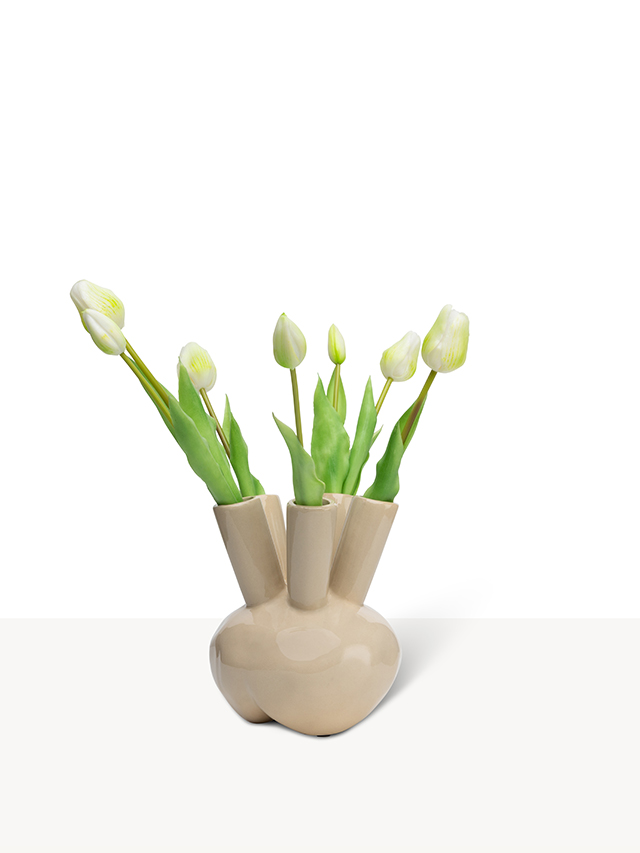 Een beige keramieken tuitvaas met vijf openingen, gevuld met zijden witte tulpen tegen een witte achtergrond.