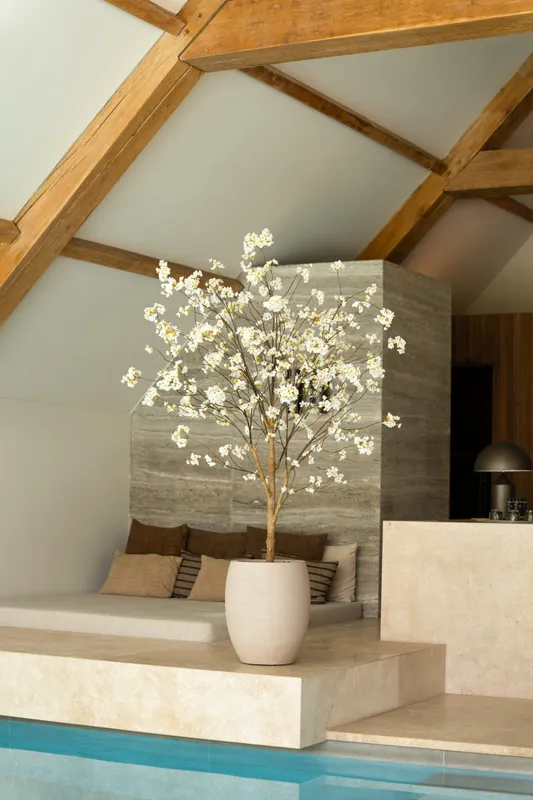 Een 180 cm hoge kunstmatige bloesemboom met crème-witte bloemen in een beige pot in een stijlvol modern interieur.