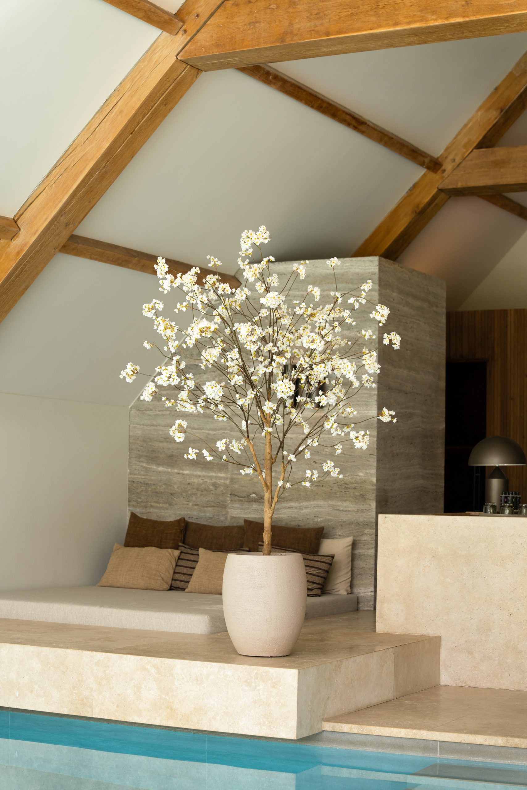 Een 180 cm hoge kunstmatige bloesemboom met crème-witte bloemen in een beige pot in een stijlvol modern interieur.