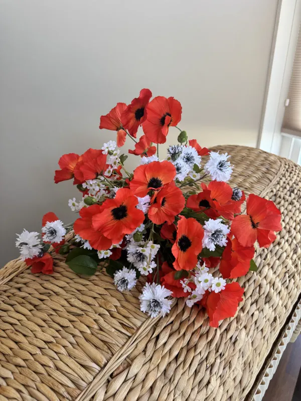 Een weids zijden boeket met felle oranjerode papavers met zwarte harten, afgewisseld met witte madeliefjes en kleine witte bloemen met donkere hartjes