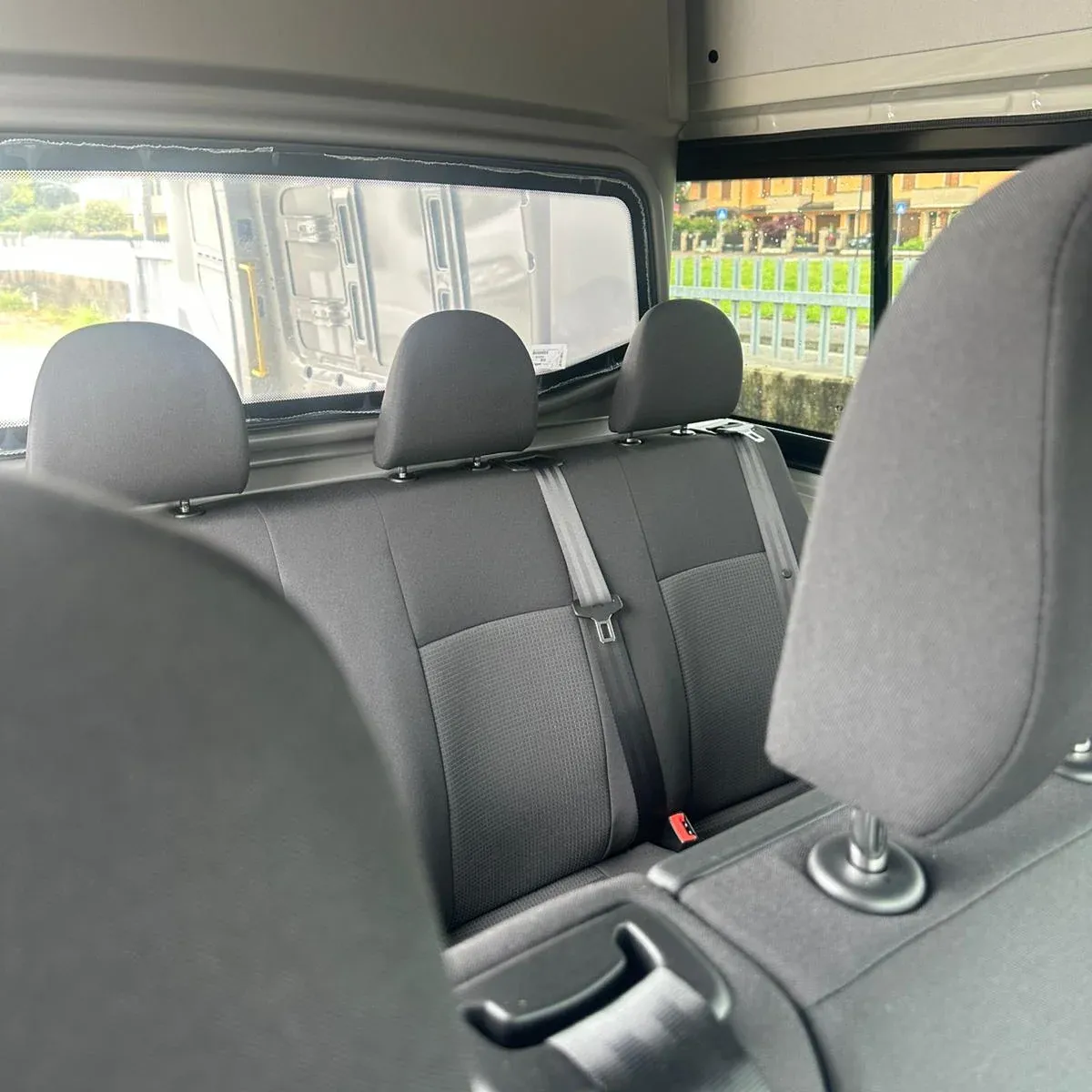 Furgone passeggeri con porta scorrevole aperta che mostra i sedili posteriori e l'allestimento interno grigio.