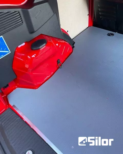 Interni di un furgone rosso con pavimento grigio.