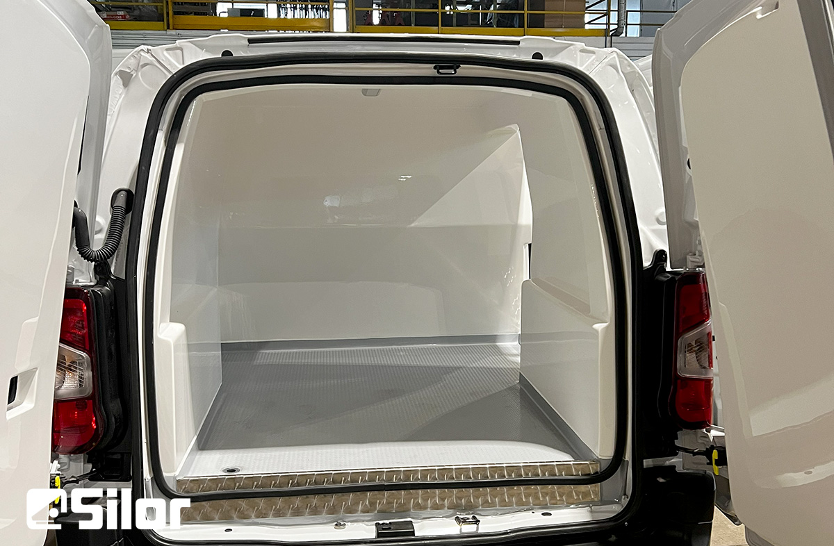 Interno di un furgone refrigerato bianco con le porte posteriori aperte.
