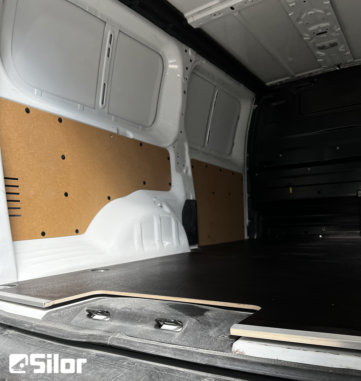 Interno di un furgone da carico bianco con pannelli in legno.