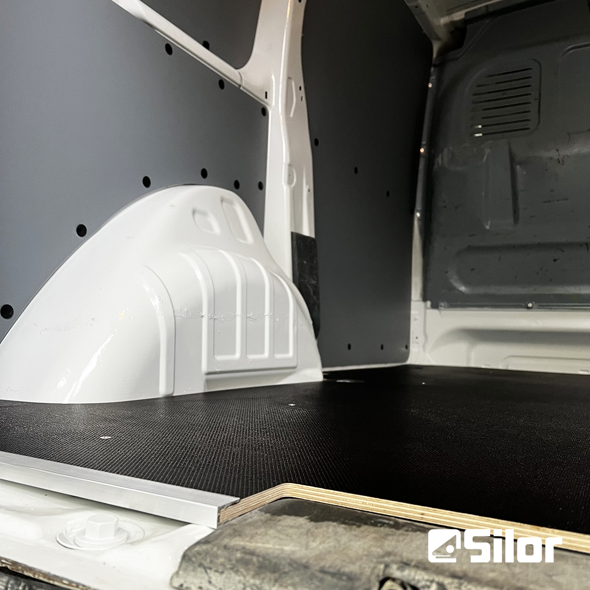 Interno di un furgone bianco con pavimento nero.