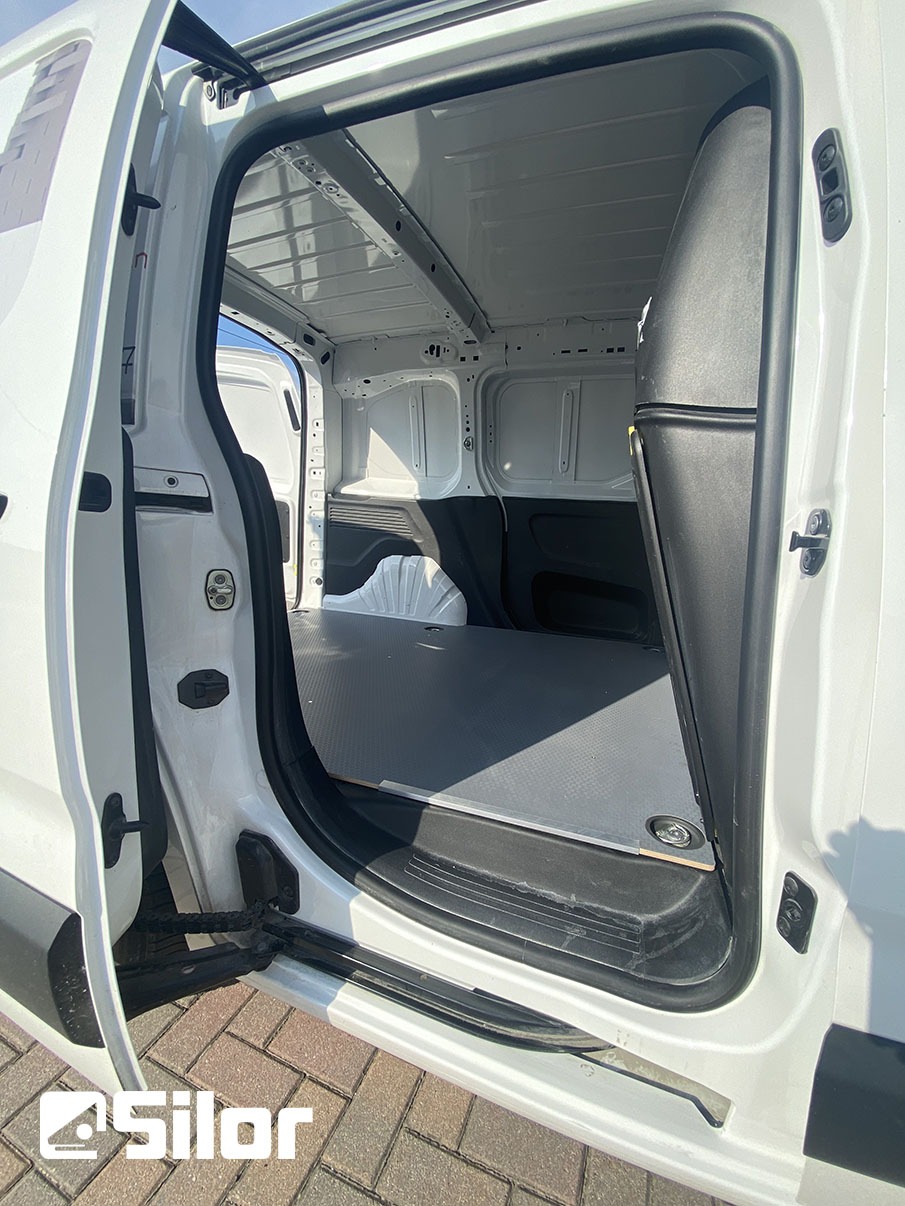 Interno spazioso di un furgone bianco con porta aperta.