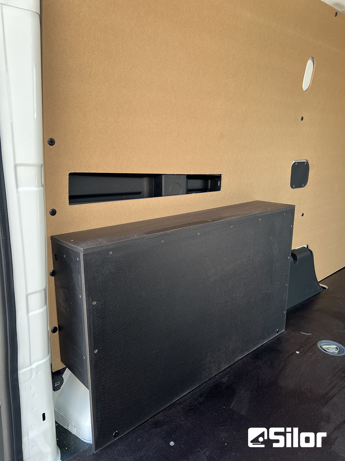 Interni di furgone convertito con pannelli di legno e scatola nera.