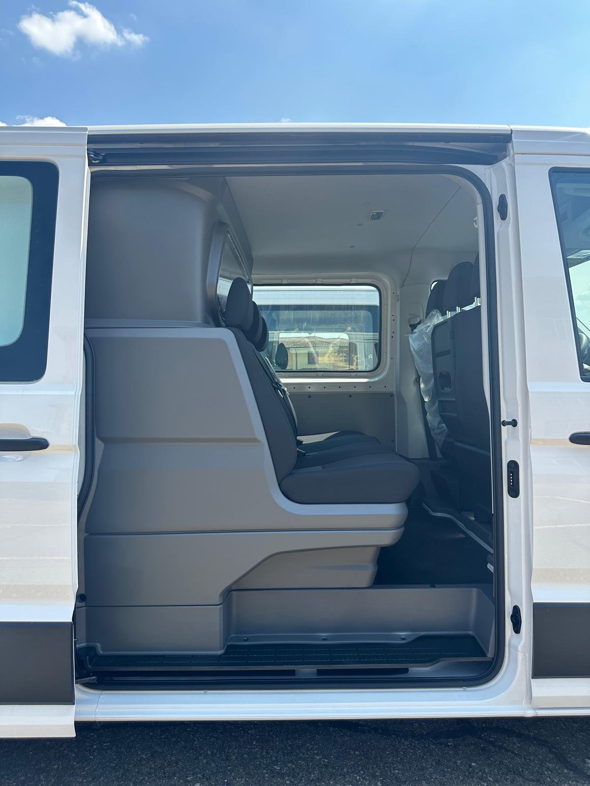 Interni di un furgone passeggeri bianco con sedili grigi.