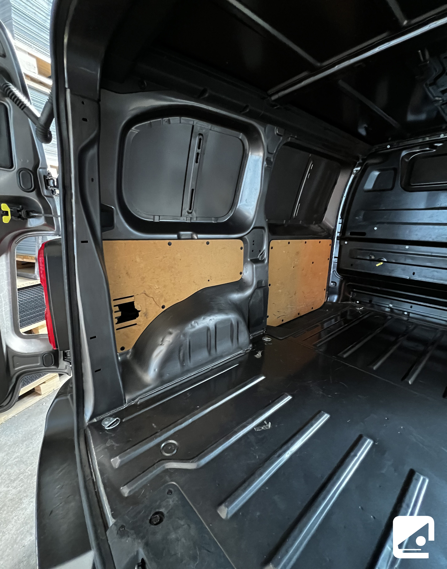 Interno di un furgone nero con pannelli di legno sulle pareti.