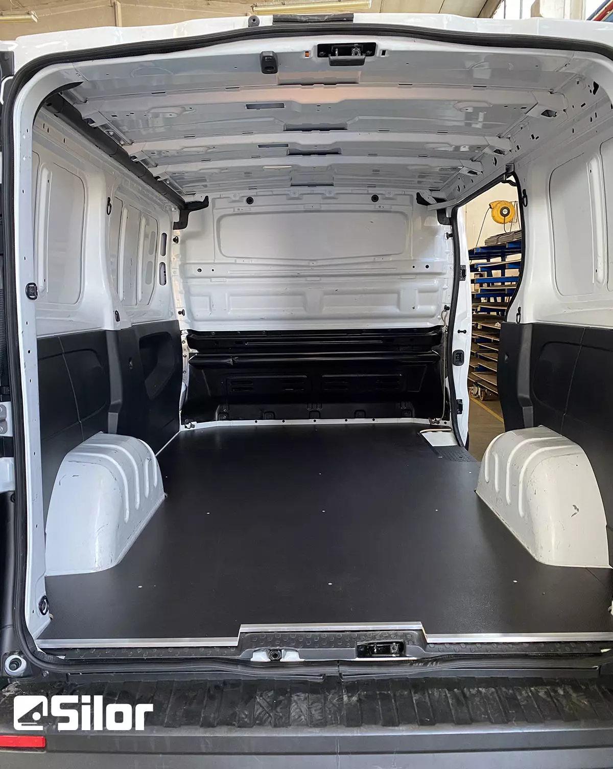 Interno spazioso e vuoto di un furgone bianco.