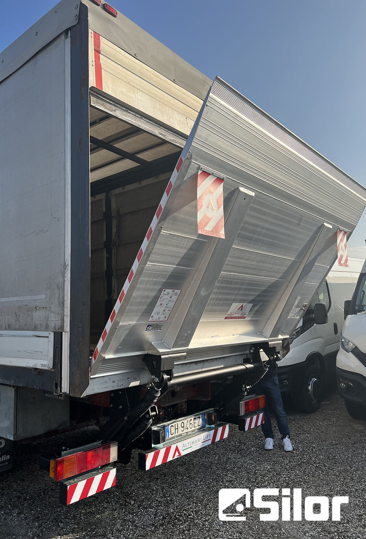 Un camion con una rampa di carico aperta. Il logo SILOR è in basso a destra.