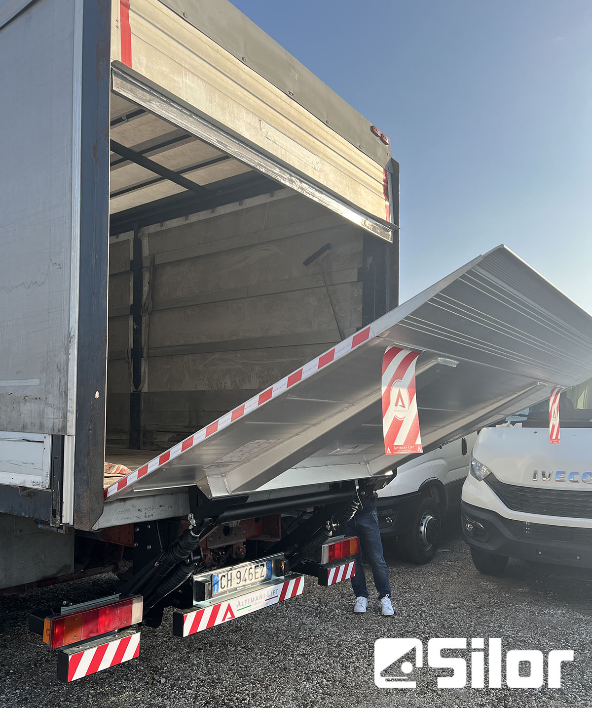 Un camion con uno scivolo aperto nella parte posteriore, che rivela l'interno.