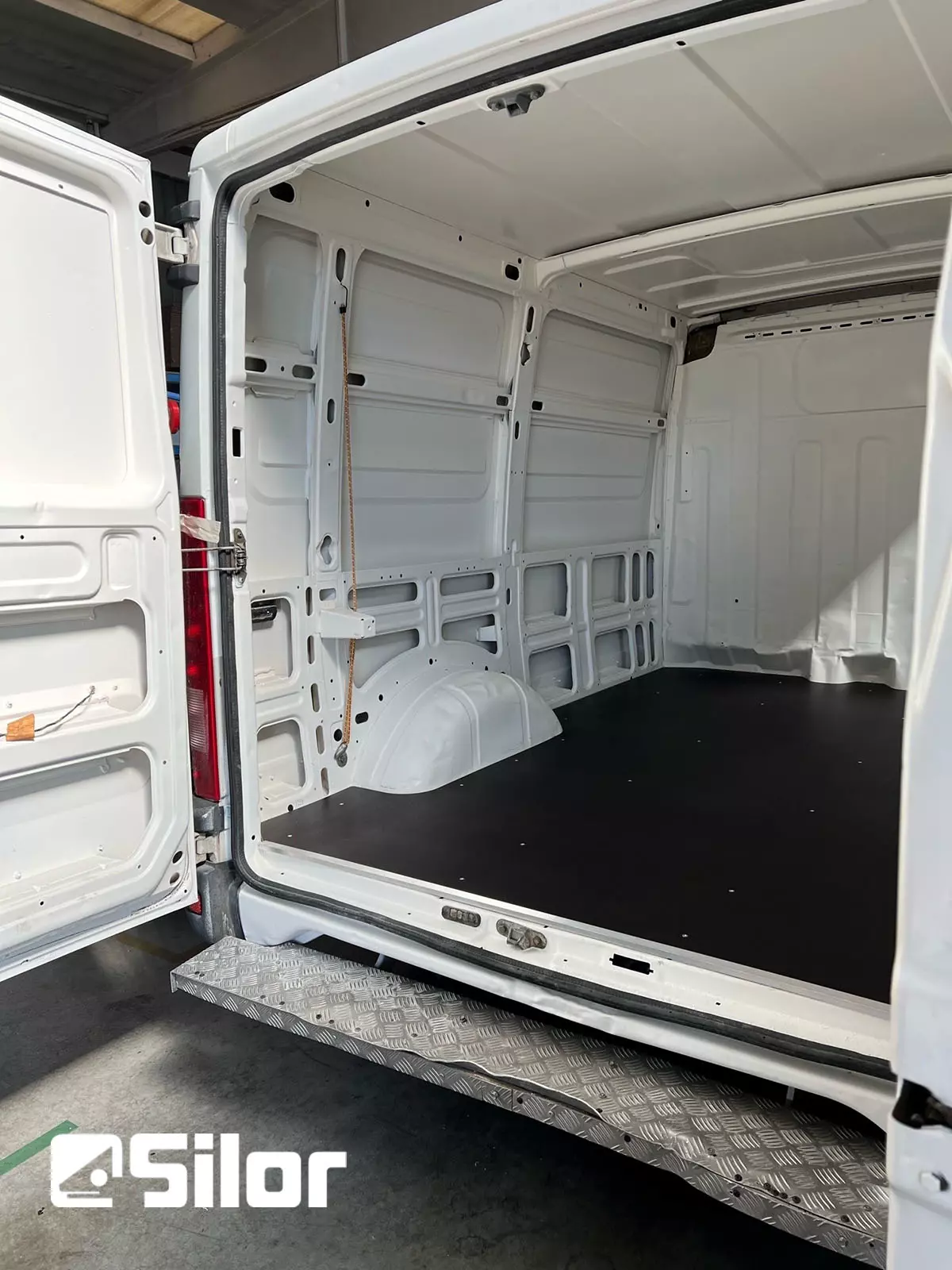 Interni furgone bianco con pavimento nero.
