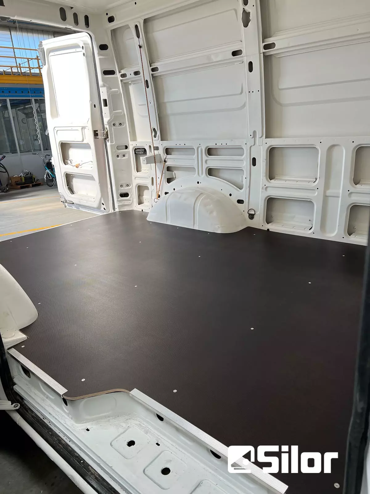 Interno di un furgone bianco con pavimento nero.