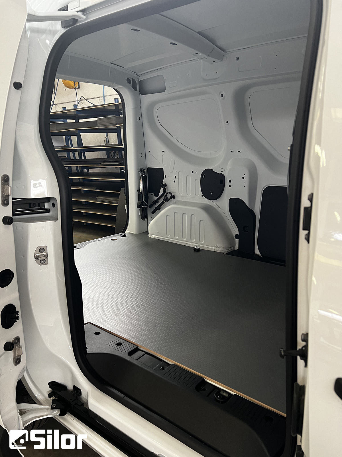 Interni di un furgone bianco con pavimento grigio.