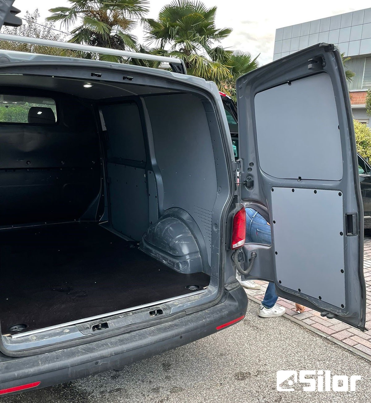 Porte posteriori del furgone aperte, che rivelano lo spazio di carico rivestito.
