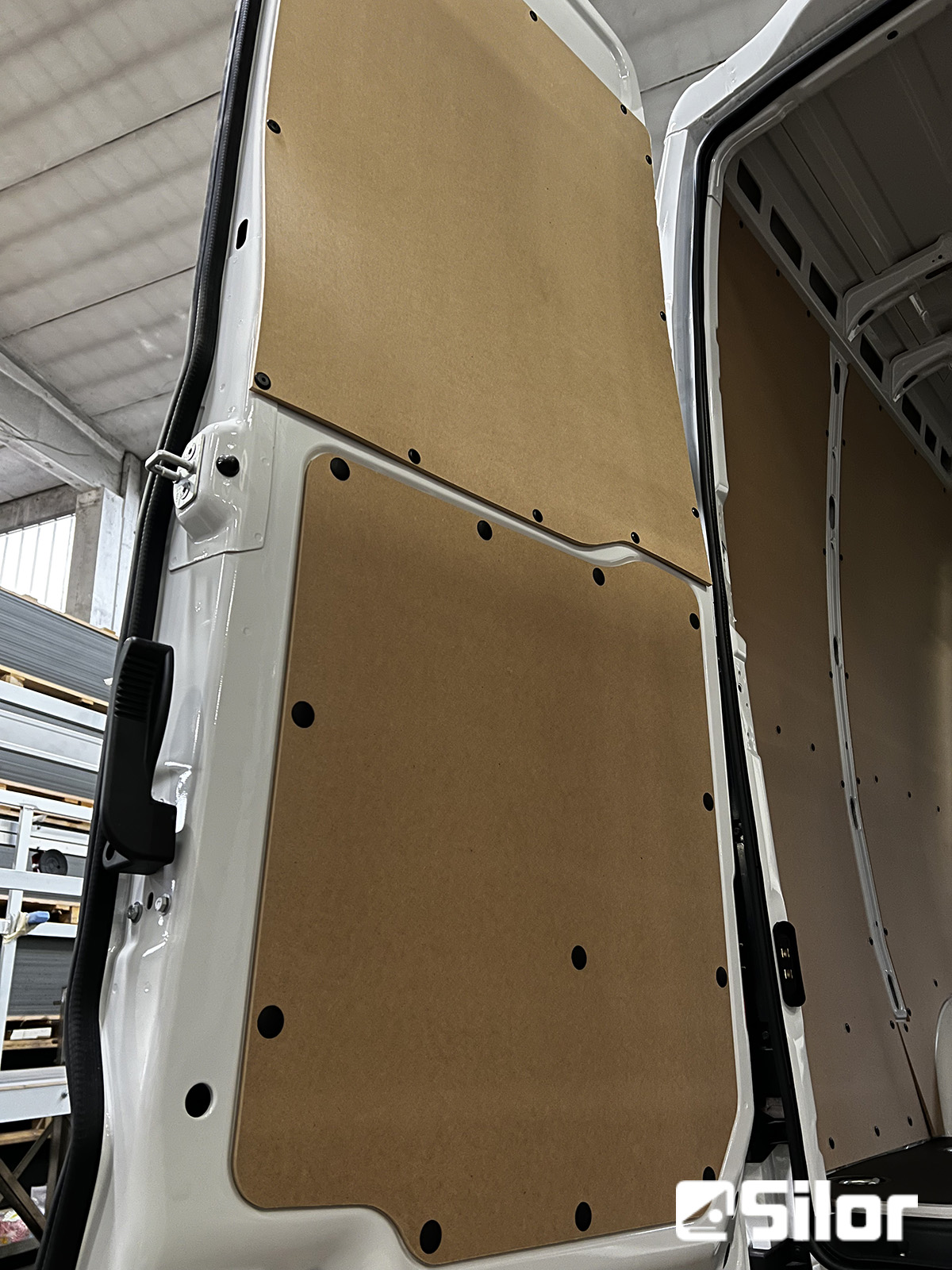 Porte del furgone rivestite con pannelli di legno marrone fissati con bulloni neri.