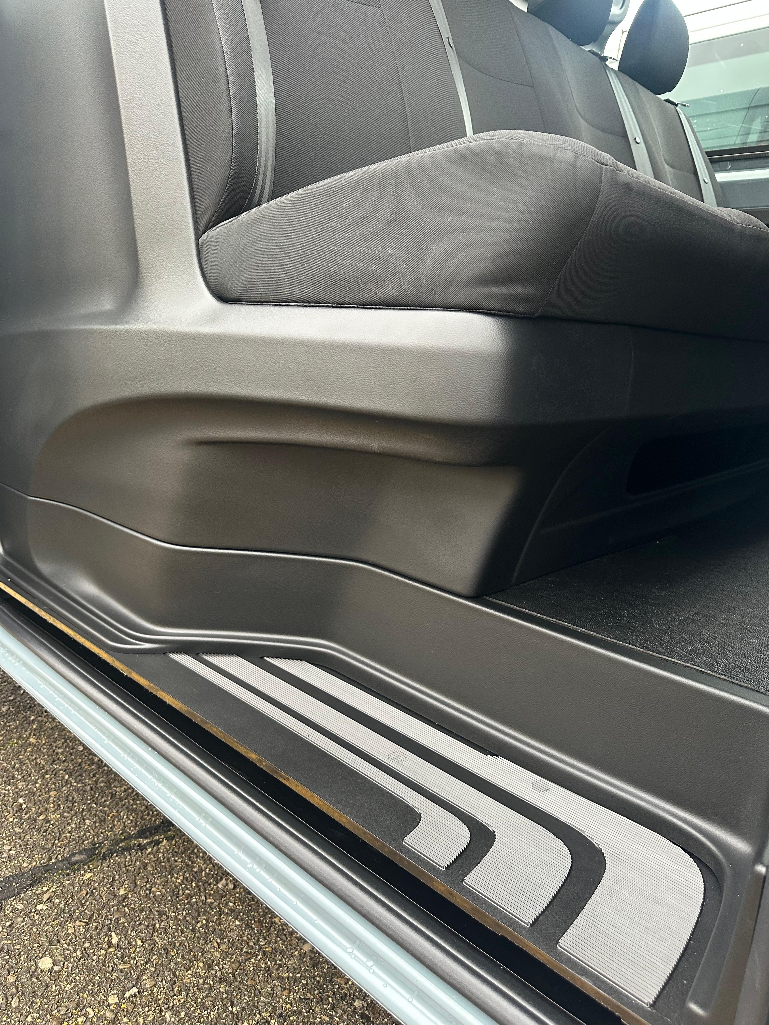 Un dettaglio dell'interno di un veicolo con sedili in tessuto grigio e rivestimenti in plastica grigio scuro.