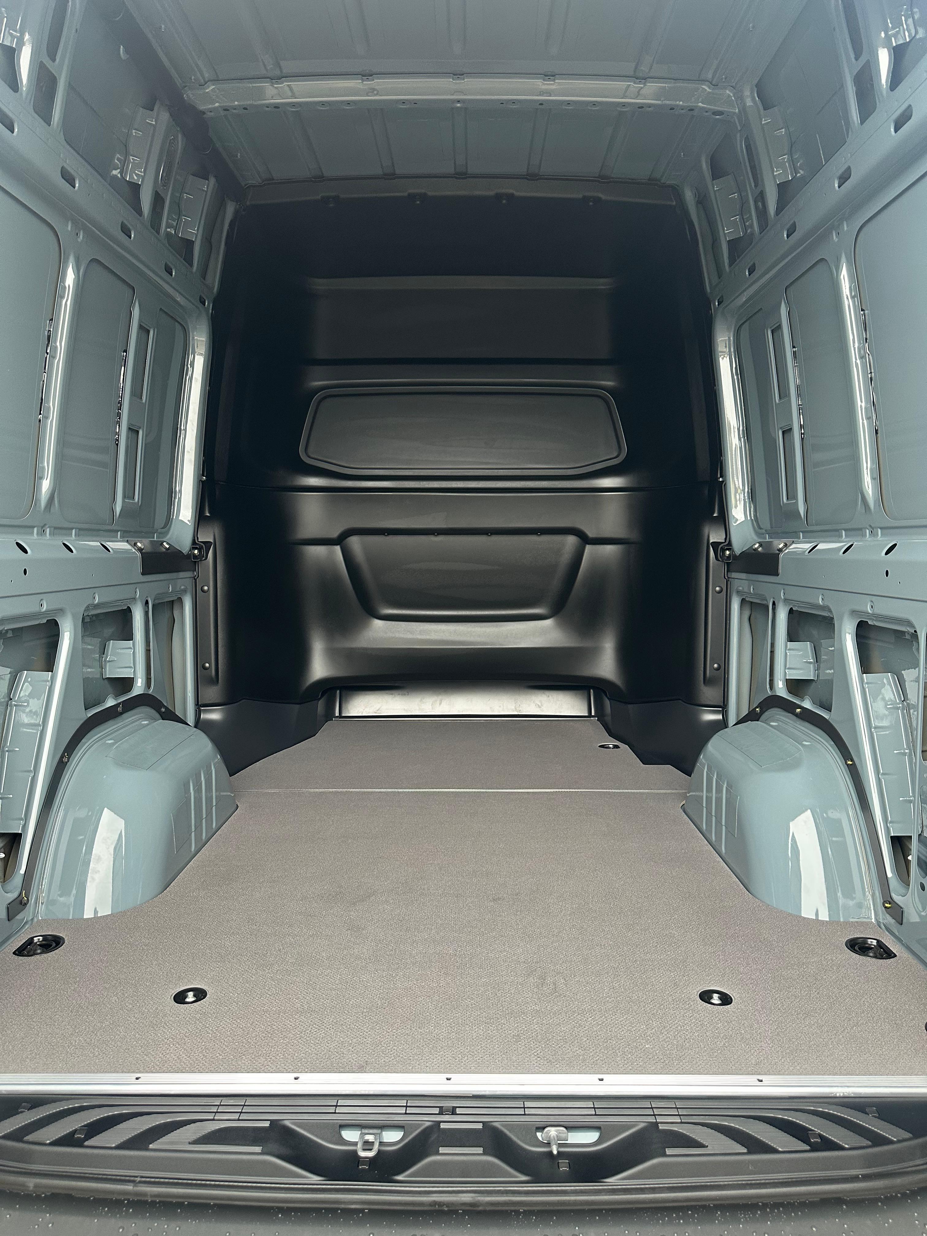 Interni del furgone vuoto con pavimento grigio e pareti grigie.