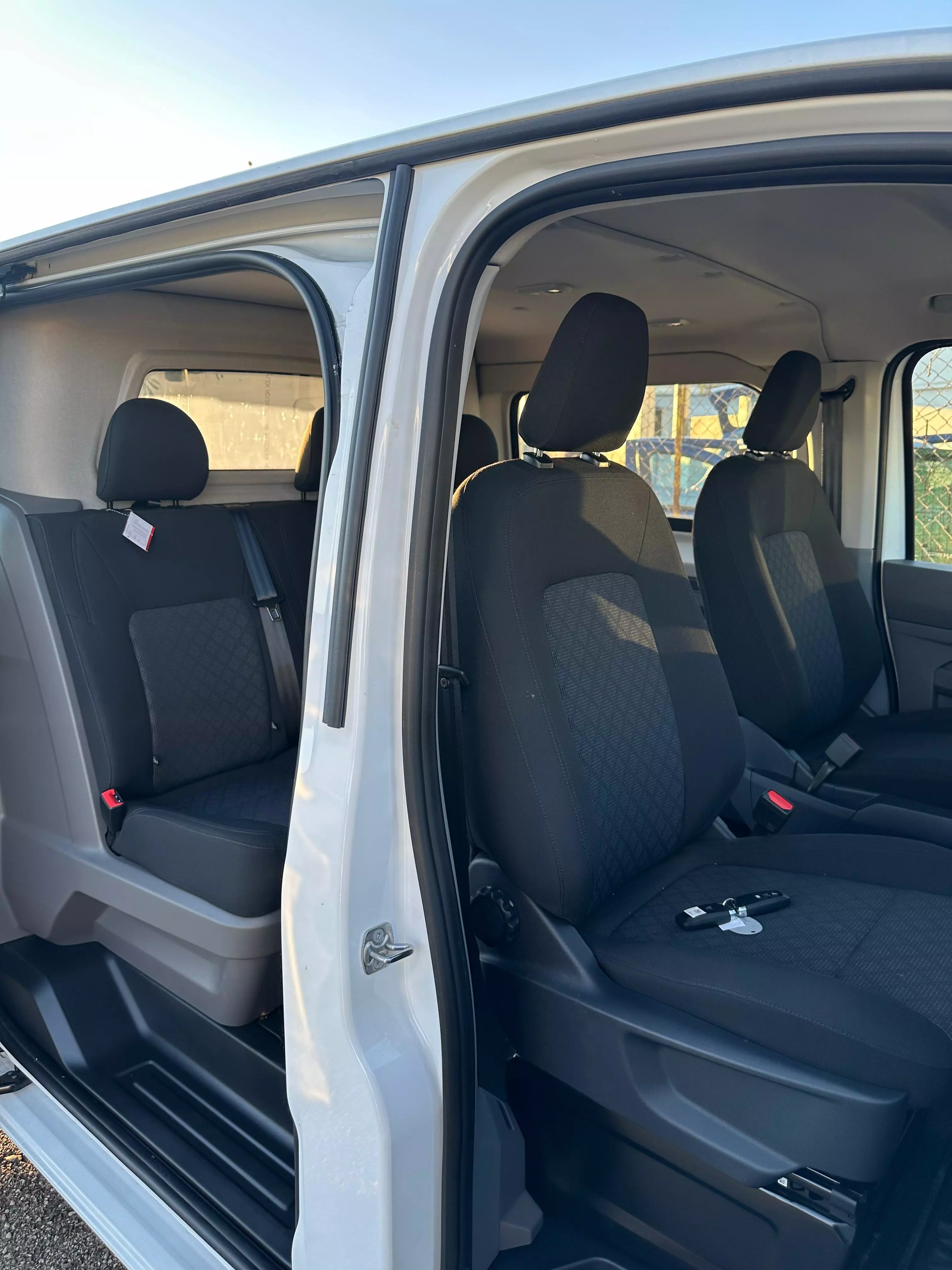 Interni di un furgone bianco con sedili neri e una chiave sul sedile del passeggero.