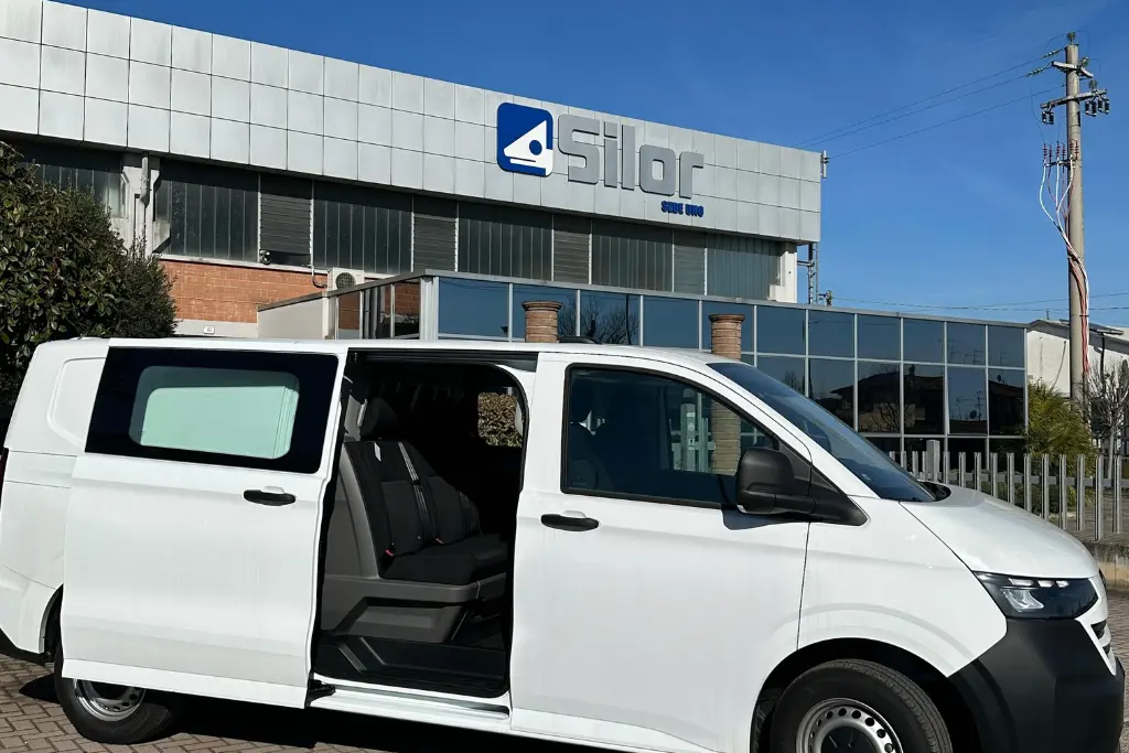 Un furgone bianco con la portiera aperta parcheggiato davanti a un edificio Silor.