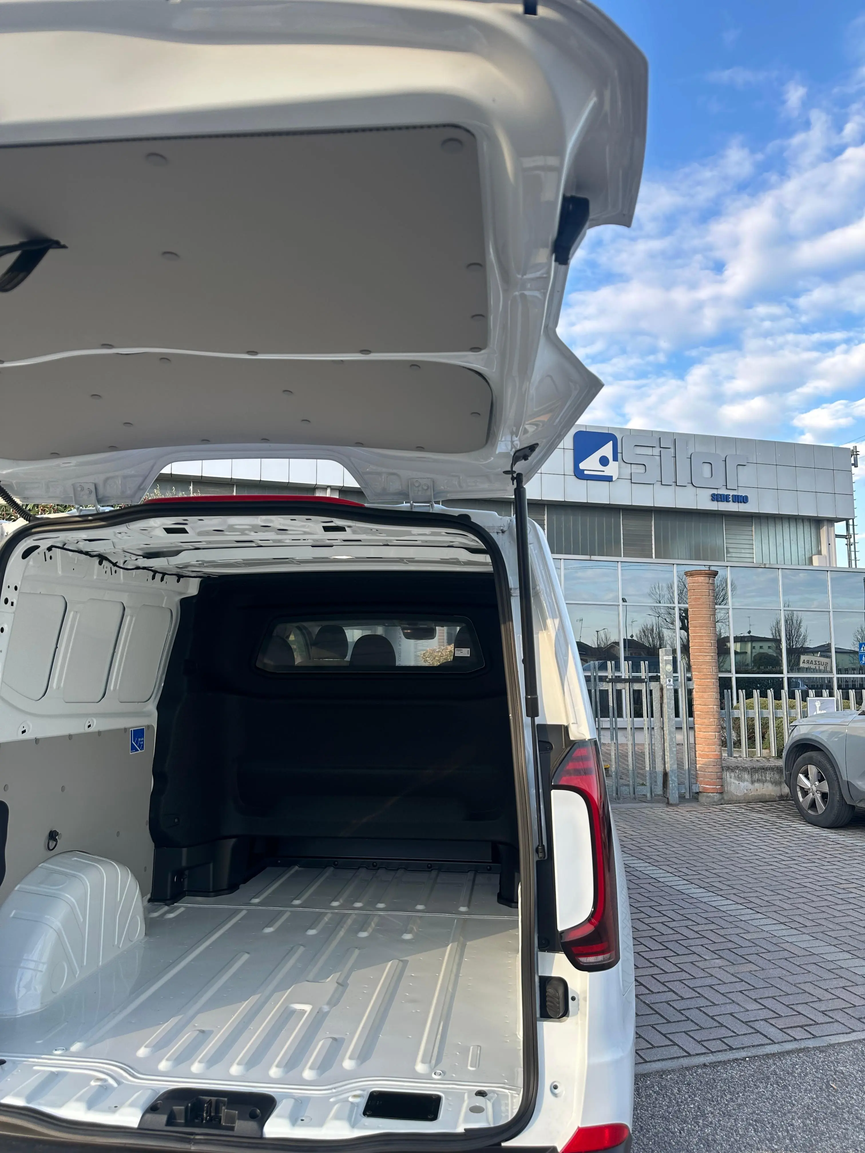 Interni di un furgone bianco con il portellone posteriore aperto.