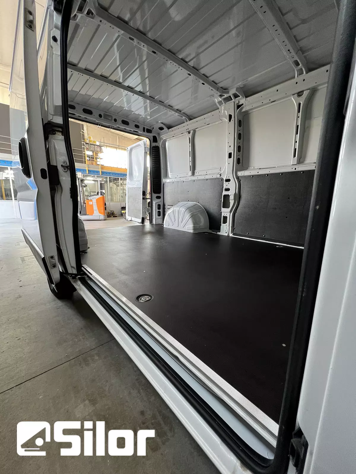 Interni di un furgone merci bianco con pavimento nero.