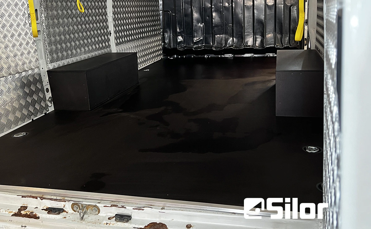 Interni di furgone con pavimento nero e scatole.