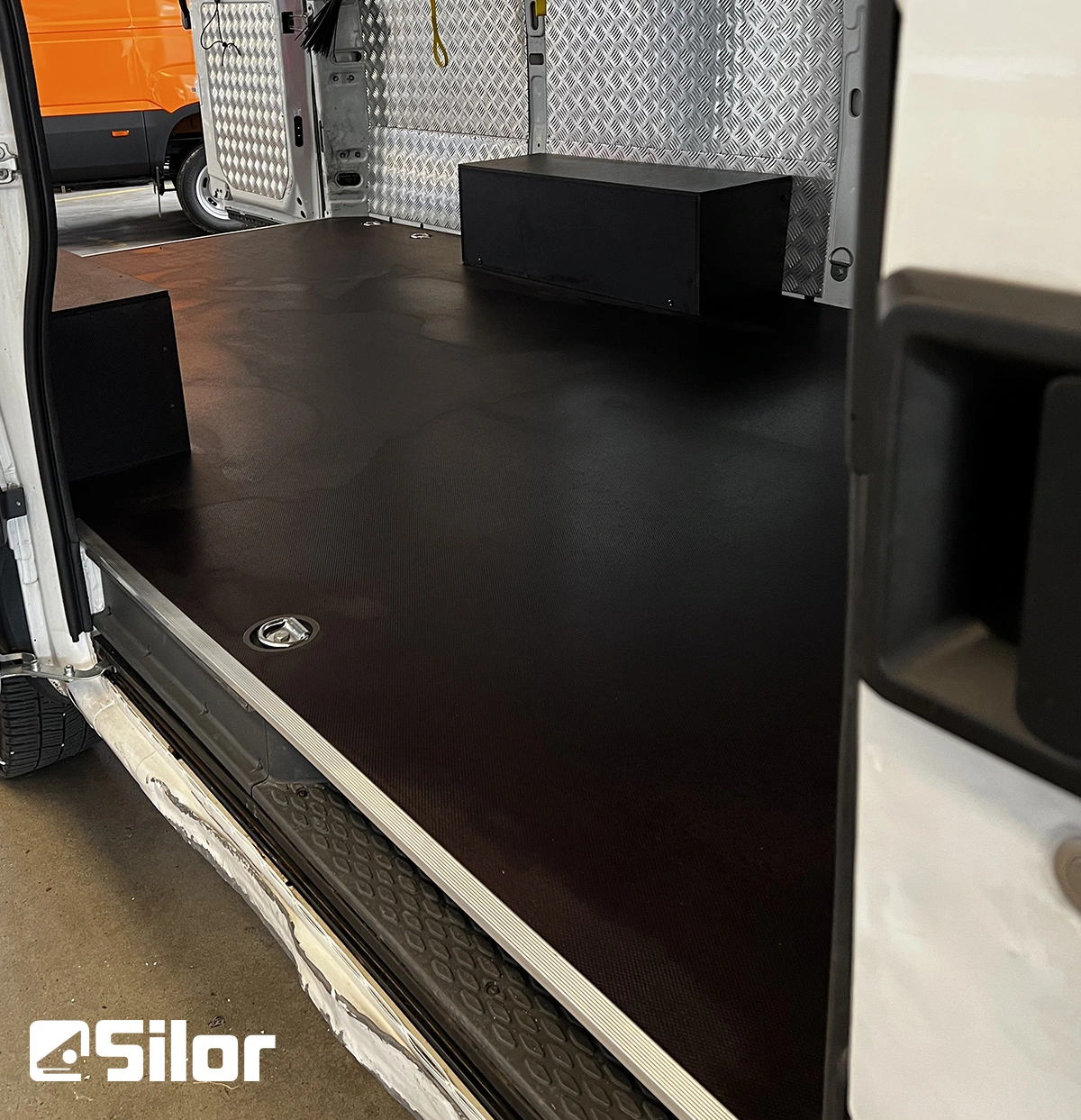 Interni di furgone con rivestimento in gomma nera e pareti metalliche.