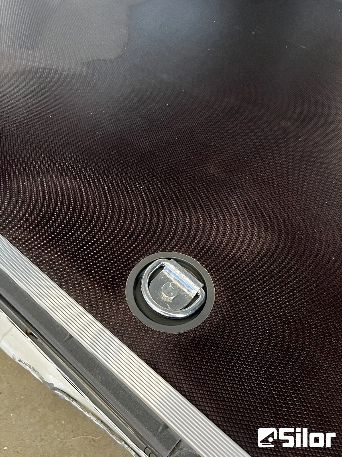 Primo piano di un punto di ancoraggio a D su una superficie testurizzata scura.