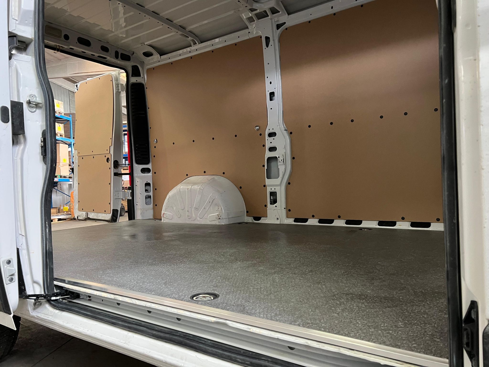 Interni di un furgone bianco con pareti in compensato e pavimento grigio.