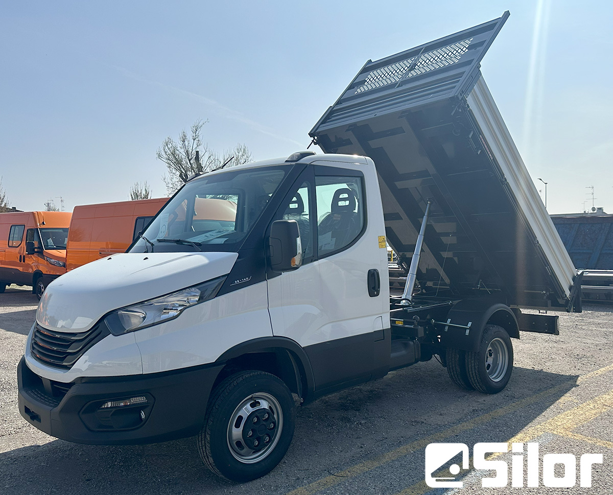 Un camion ribaltabile bianco su un parcheggio con il cassone sollevato.