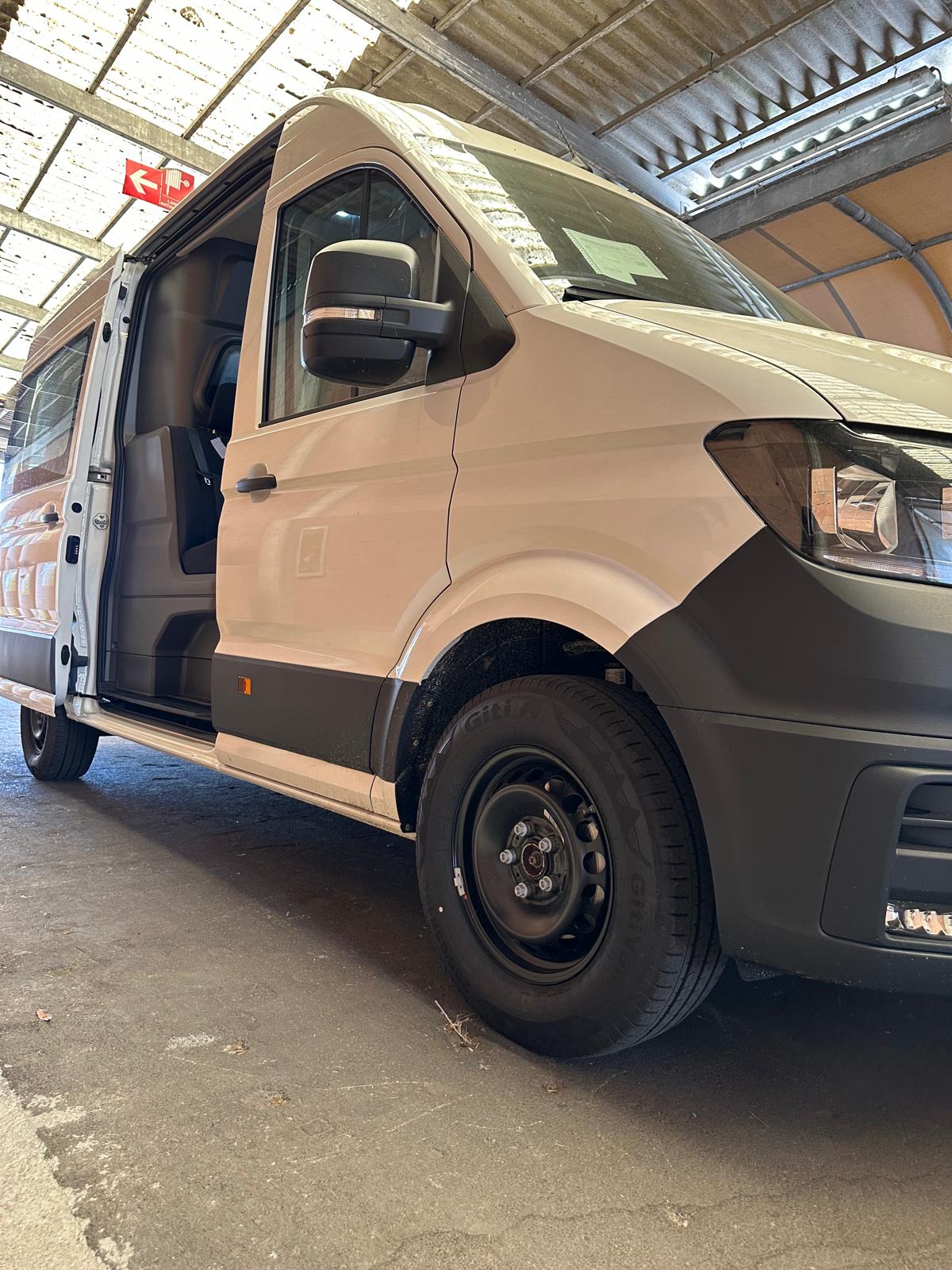 Un furgone bianco è parcheggiato con la portiera del guidatore aperta.