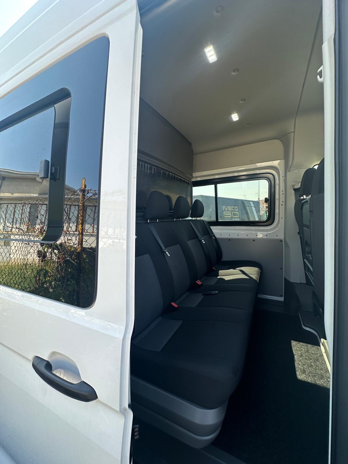 Interno spazioso di un furgone con comodi sedili e illuminazione luminosa.