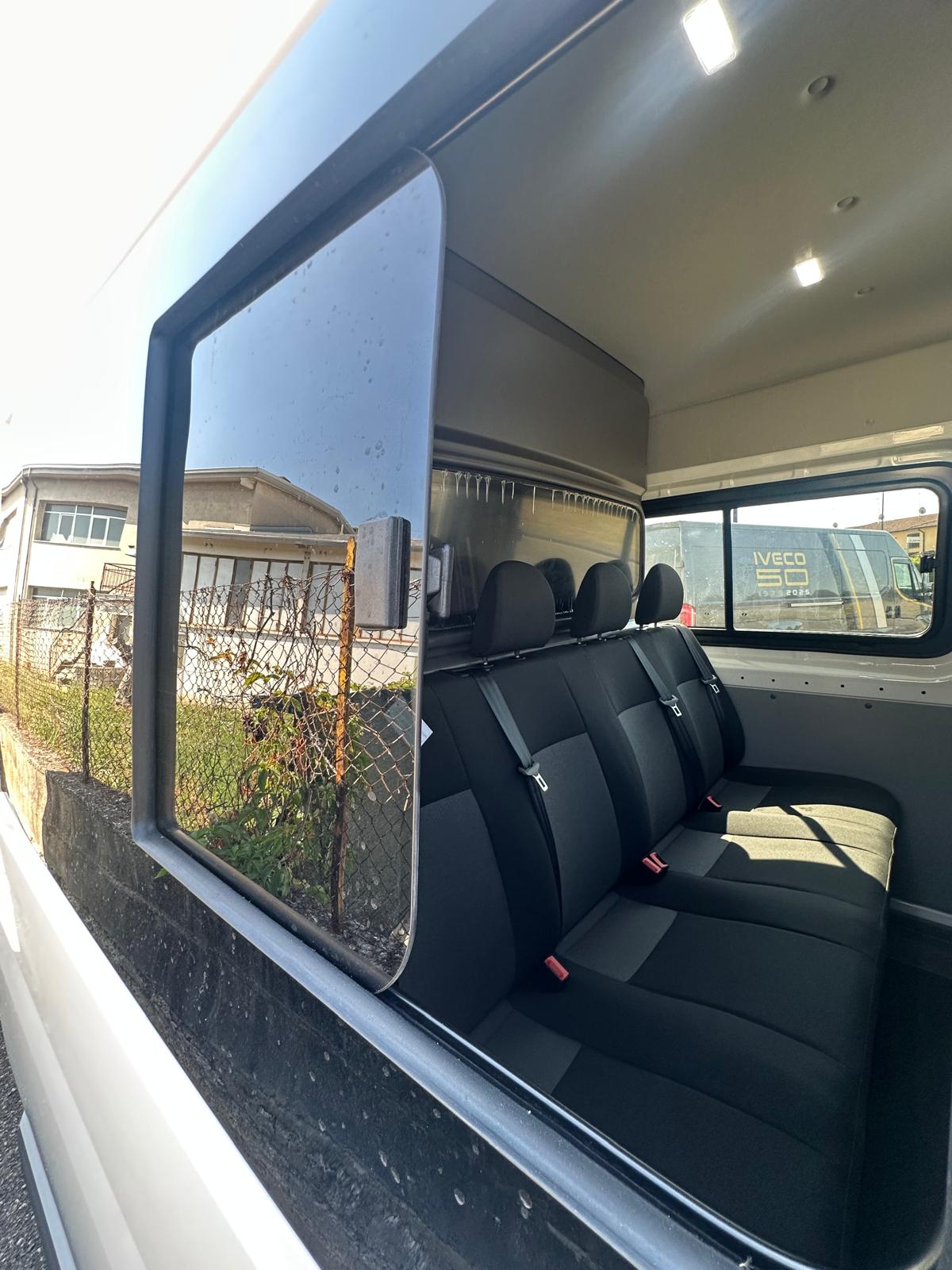 Interni di un furgone bianco con tre sedili in fila.