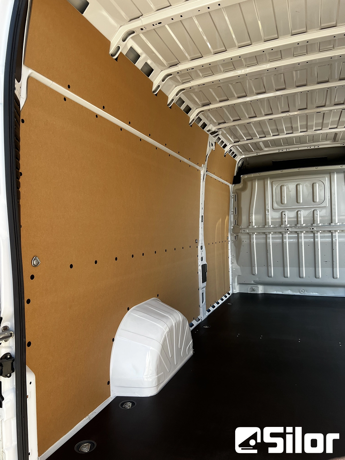 Interno di un furgone bianco con pannelli marroni e pavimento nero.