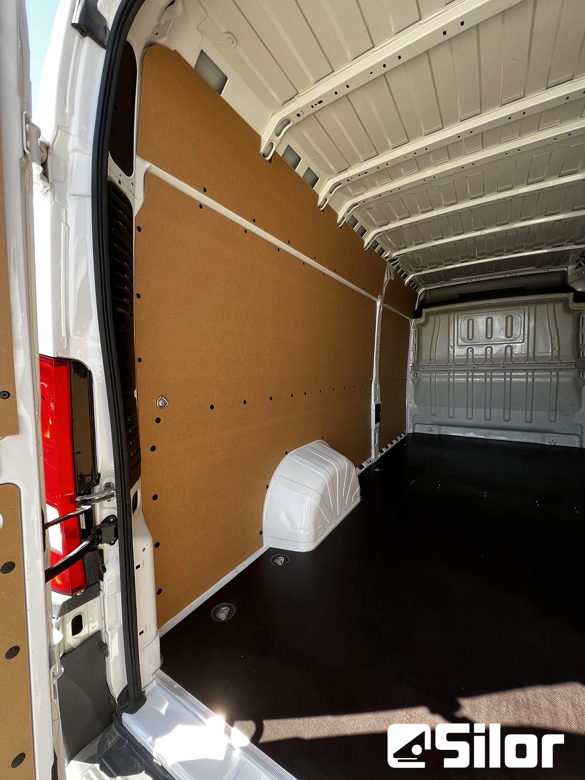 Interni di furgone personalizzati con pannelli marroni e pavimento nero.