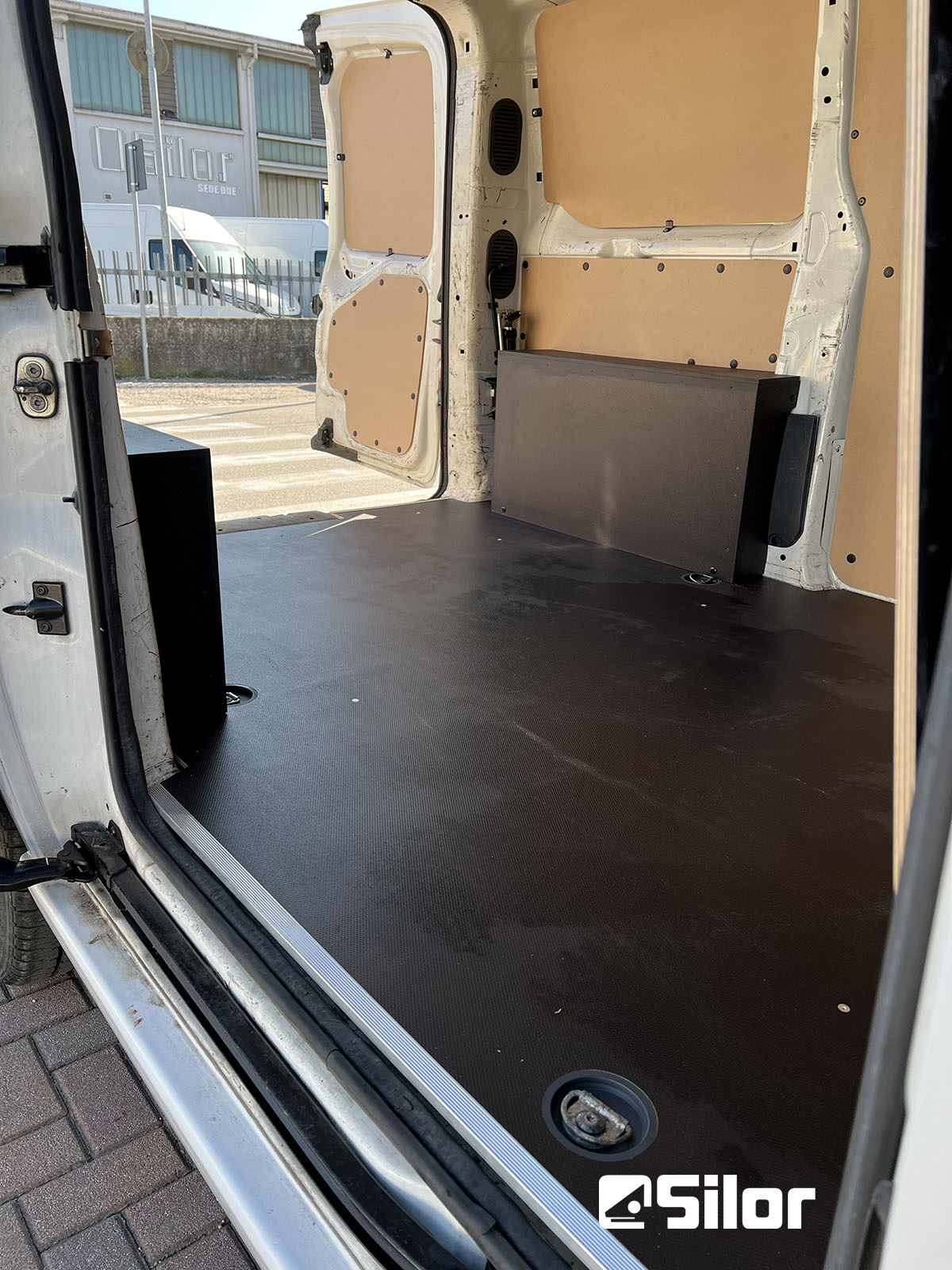 Interno di un furgone commerciale con rivestimento in legno e gomma.