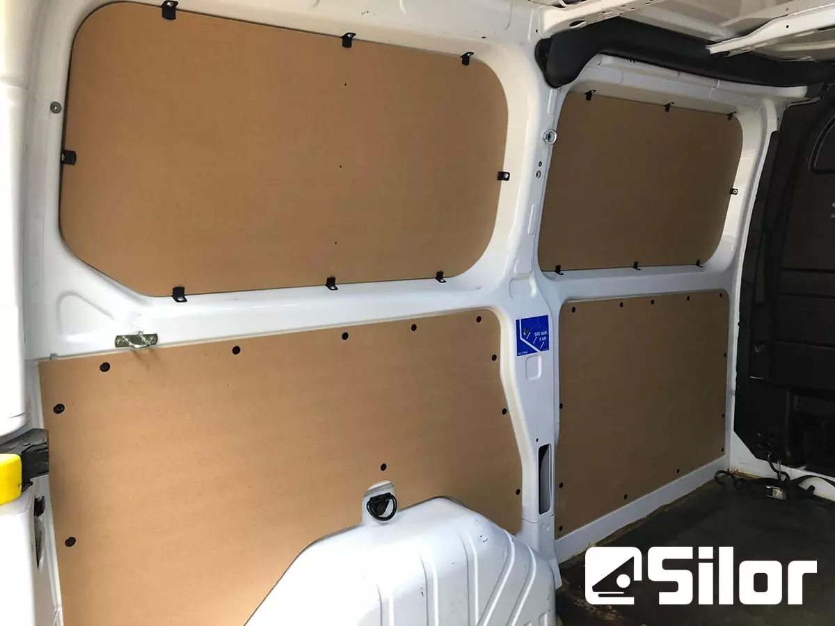 Interni di un furgone bianco con pannelli di legno sulle pareti.