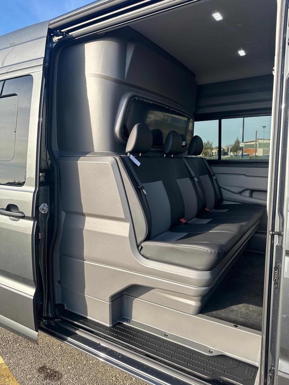 Interno di un furgone passeggeri con sedili rivestiti in grigio e luci a LED sul tetto.