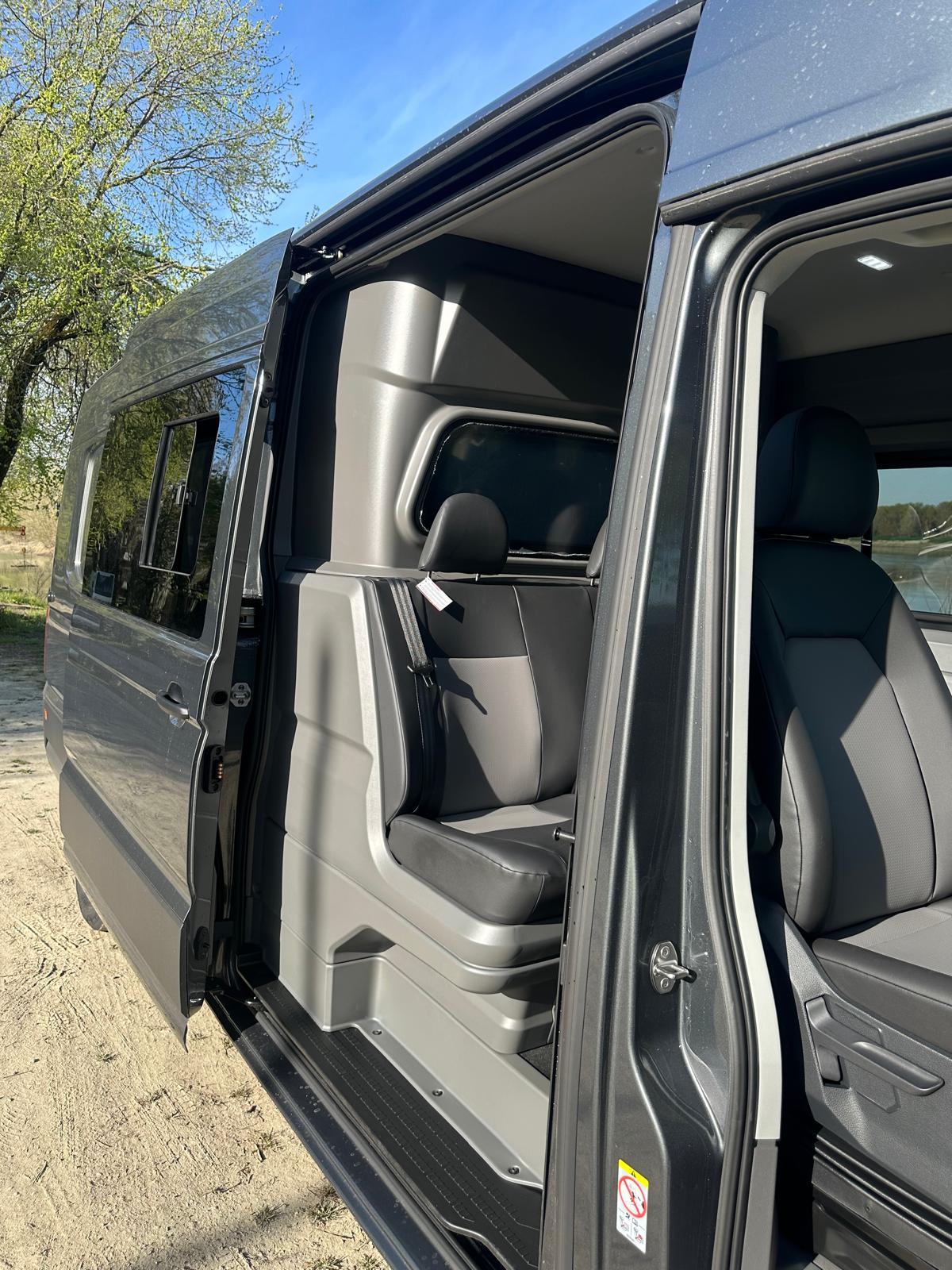 Interno di un veicolo passeggeri grigio con sedili in pelle.