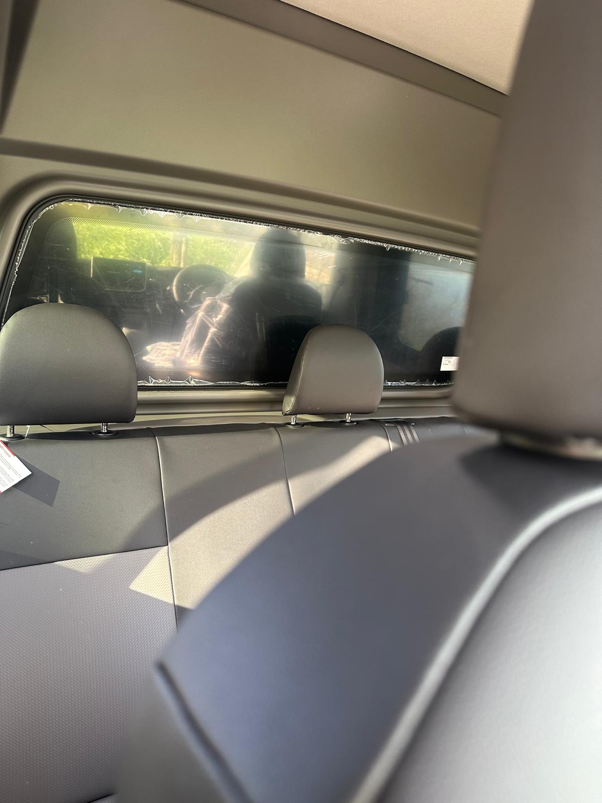 Interno di un'auto con sedili posteriori neri e lunotto.