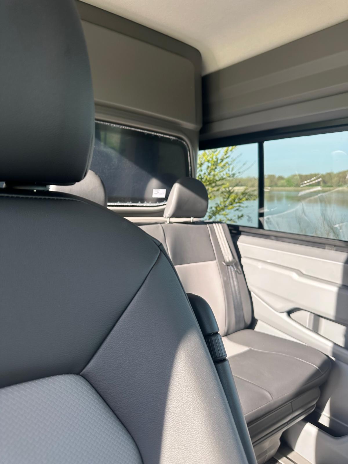 Interni di un veicolo con sedili in pelle grigia e vista sul lago.