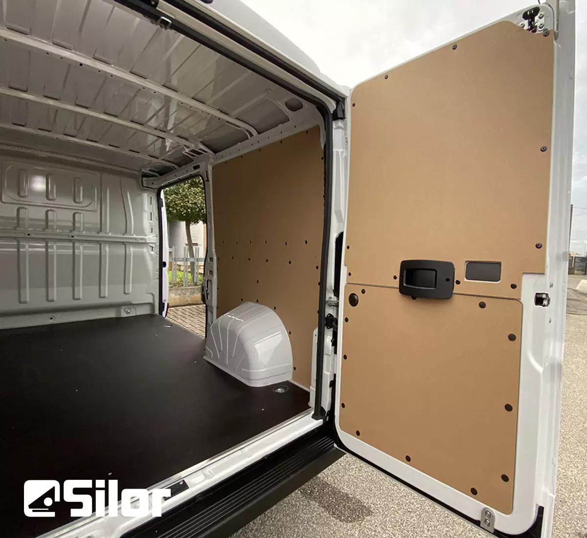 Interni di un furgone bianco con pareti in legno e pavimento nero.