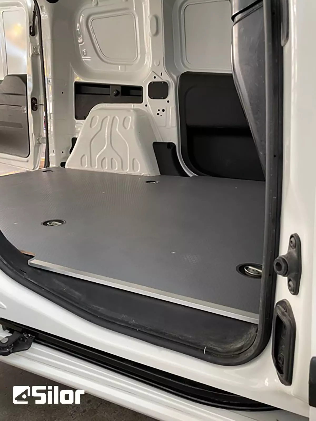 Interno di un furgone bianco con pavimento grigio.