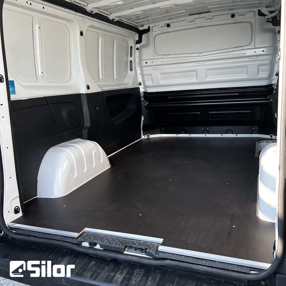 Interni di un furgone bianco con pavimento nero.
