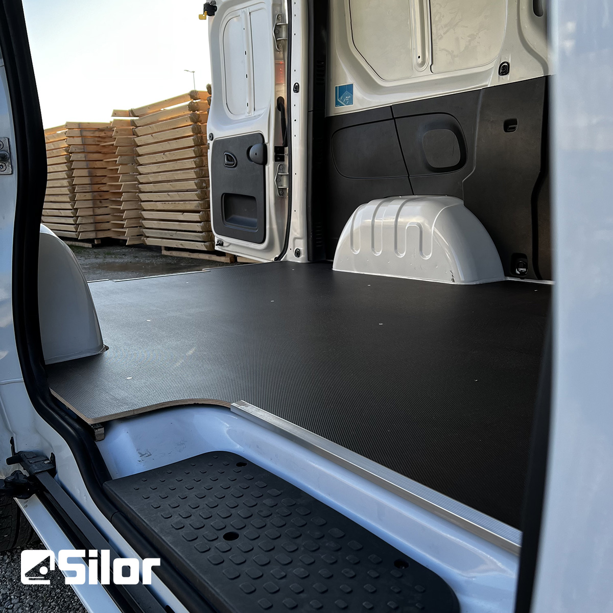 Interni di un furgone bianco con pavimentazione nera.