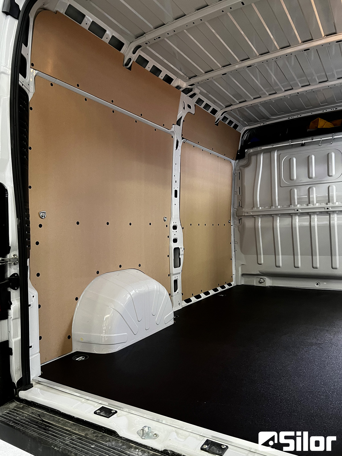 Interno di furgone rivestito in legno e con pavimento nero.